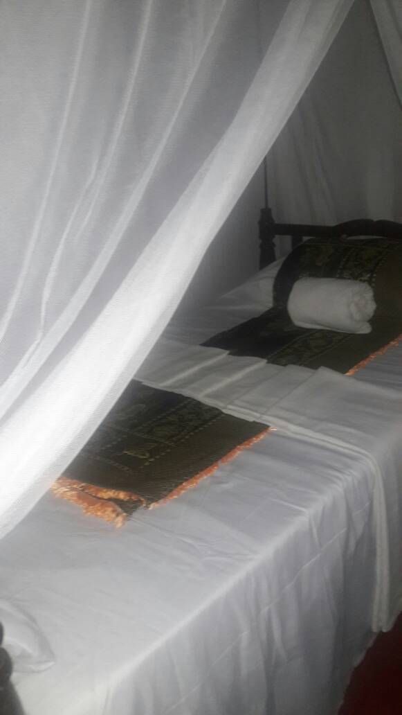 A bed with a white bedspread and a rolled-up towel.