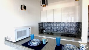 Een moderne keuken met witte kastjes, een decoratieve spatwand en een magnetron op het aanrecht.