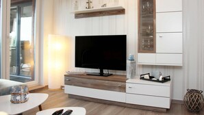 Een moderne woonkamer met een flatscreen televisie, houten kasten en een glazen displayplank.