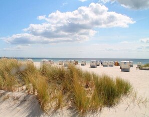 A beach with white beach chairs and umbrellas arranged in rows. - Modern 70 m² vacation rental with a rooftop terrace in Grömitz / Brenkenhagen and a Wallbox (Brenkenhagen)