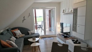 Een moderne woonkamer met een bank, een televisie en een eethoek met een tafel en stoelen.