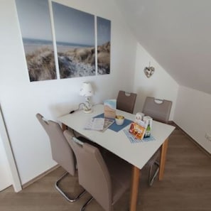 Un coin repas comprenant une table, des chaises, une lampe et donnant sur la plage.