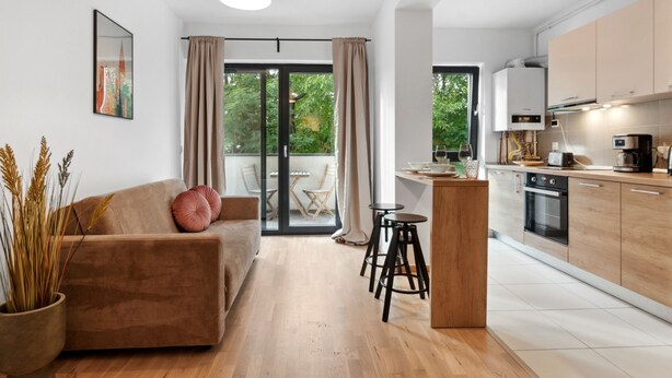 Un apartamento moderno con sala de estar, cocina y puerta corrediza de vidrio que da a un balcón.