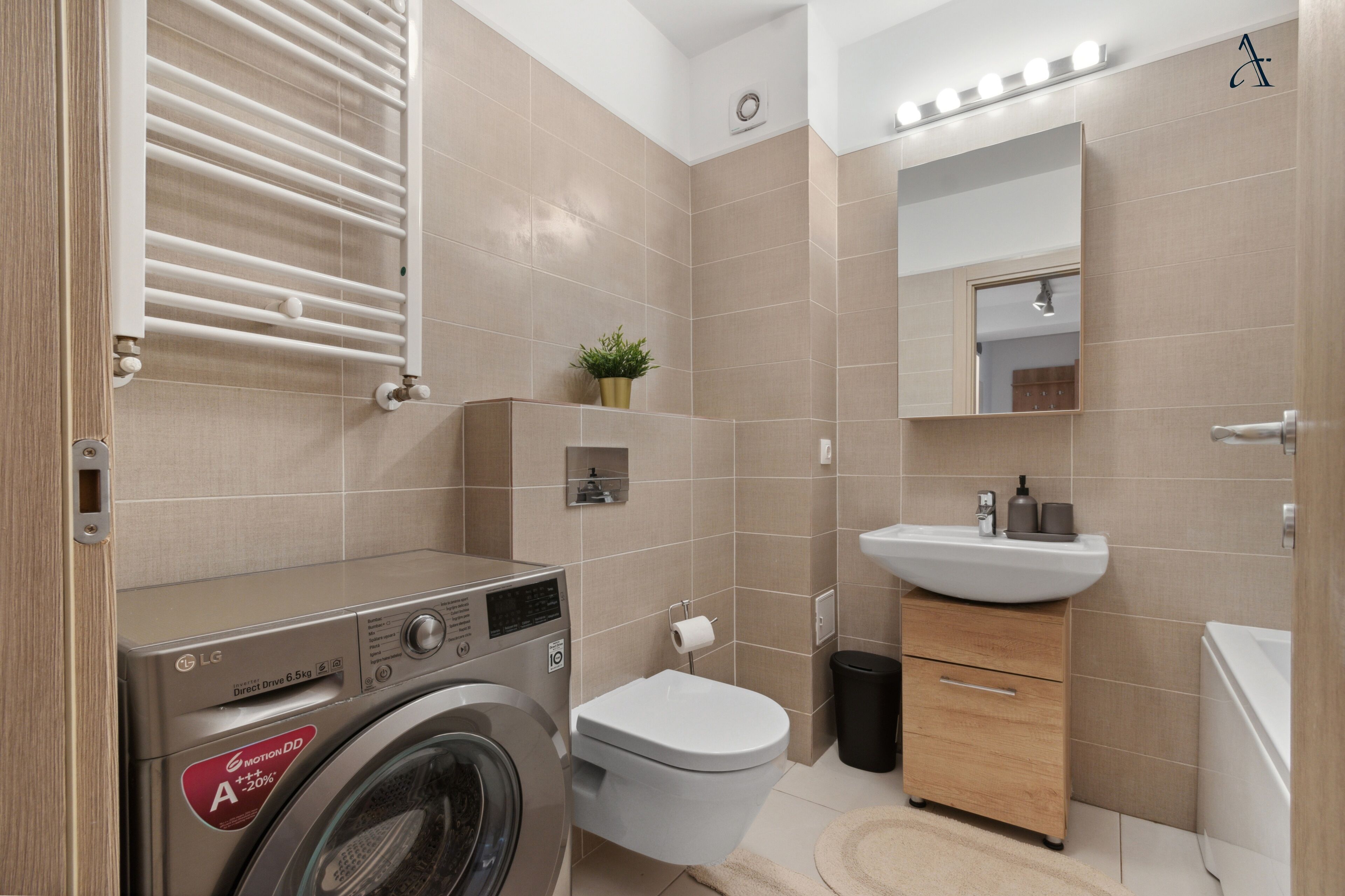 Ein modernes Badezimmer mit Waschmaschine, Toilette, Waschbecken und Spiegel.
