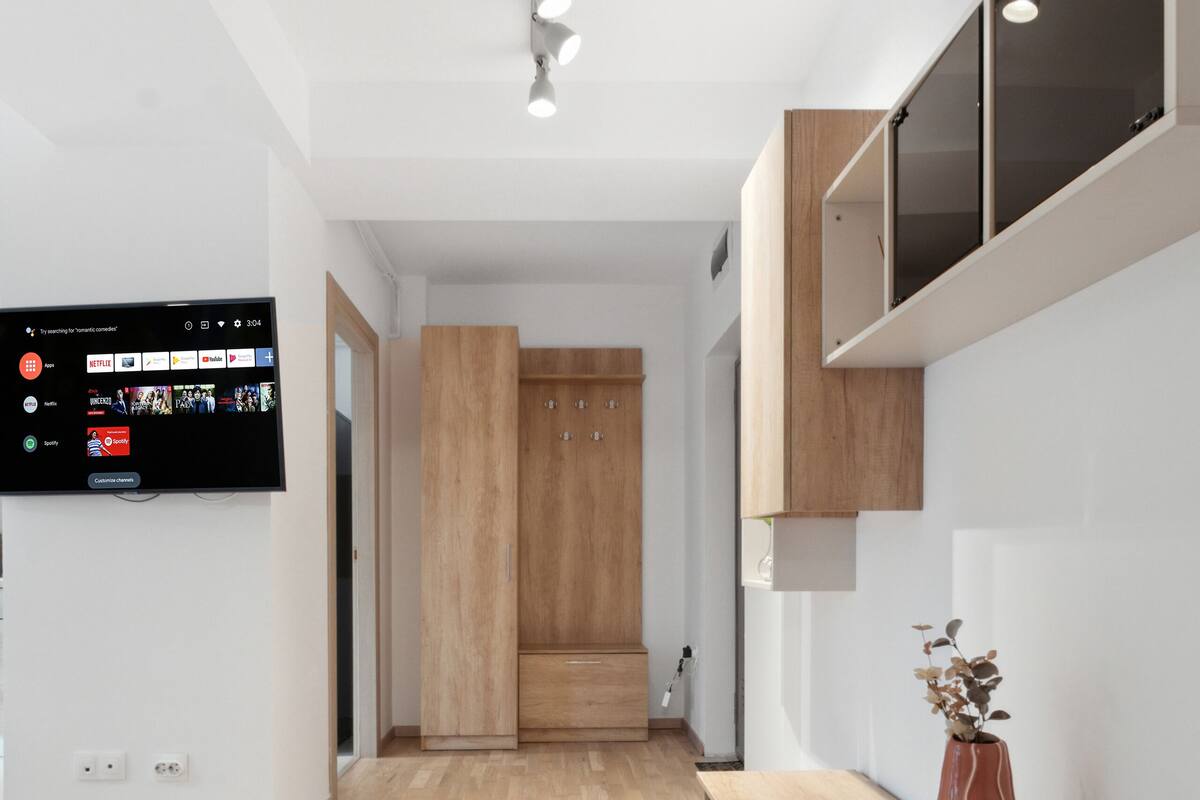 Una cocina moderna con suelo de madera, televisión integrada y un florero con flores secas en la encimera.