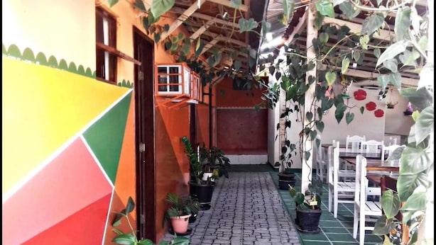 Um corredor estreito com piso de azulejos, plantas em vasos e móveis brancos.