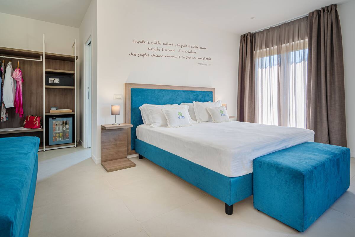 A modern bedroom with a large bed, a wardrobe, and a bedside table.