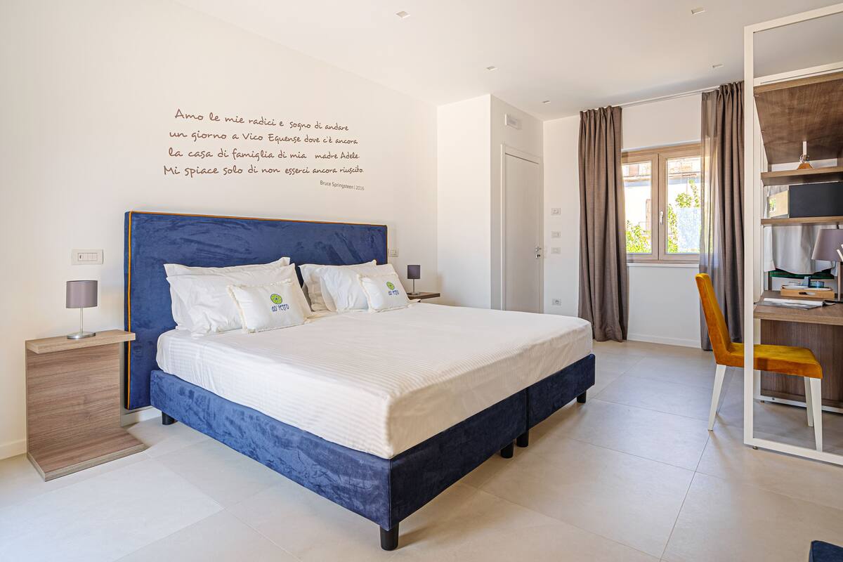 A bedroom with a large bed, a desk, and a chair.