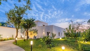 A modern building with a pathway leading to the entrance, surrounded by well-maintained grass and trees. - Do'Petro (Vico Equense)
