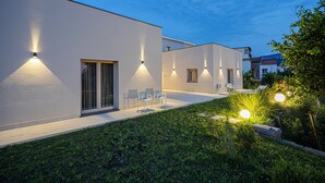 A modern building with exterior lighting, a grassy area, and outdoor seating. - Do'Petro (Vico Equense)