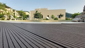 A wooden deck with lounge chairs and a pool area in the background. - Do'Petro (Vico Equense)