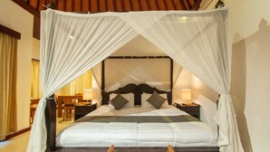 Una cama con dosel y cortinas, mesitas de noche con lámparas, una silla de madera y un escritorio con una silla.