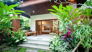 Una escalera de madera conduce a una zona de estar al aire libre cubierta, con una cama y una mesa.