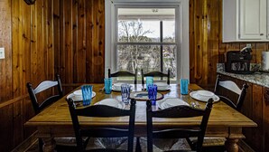 Una mesa de madera para comer con sillas, vasos azules y platos dispuestos para cuatro personas.