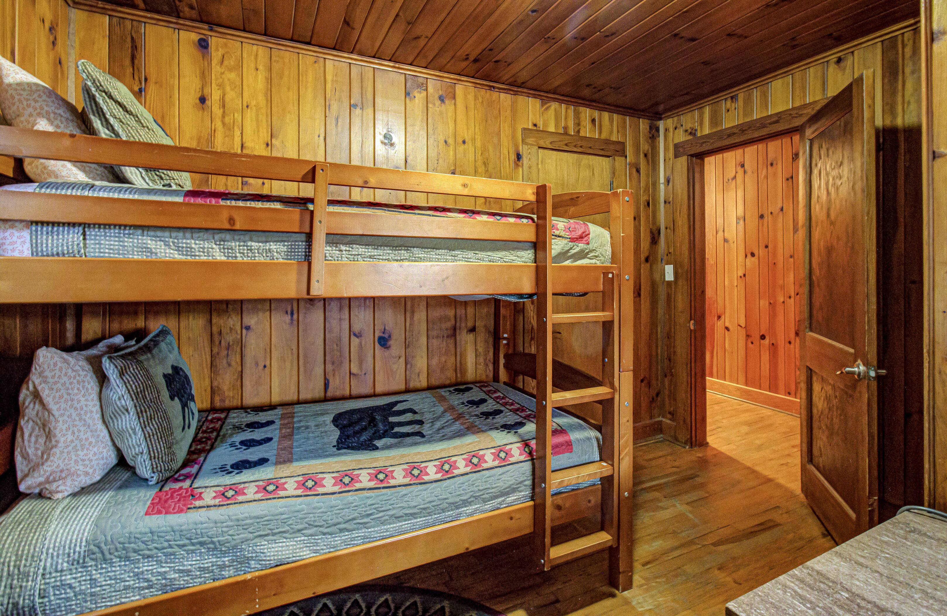 Une chambre avec un lit superposé en bois, une porte et une petite table.