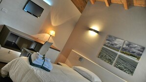 Ein Hotelzimmer mit Bett, Nachttisch, Lampe, Wand-Fernseher und einem Fenster mit Blick auf ein Feld.