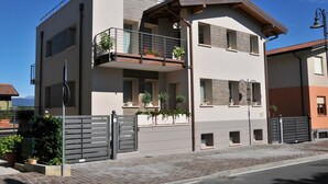 Ein modernes, zweistöckiges Haus mit Balkon, geschlossenem Eingangsbereich und freiem Blick auf die Umgebung.