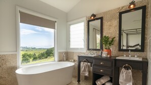 A modern bathroom with a freestanding bathtub, dual sinks, and large mirrors. - Enjoy this piece of paradise and immerse yourself in luxury and style. (Byron Bay)