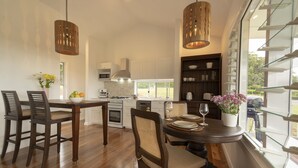 A modern kitchen with wooden cabinets, a dining table with chairs, and pendant lighting. - Enjoy this piece of paradise and immerse yourself in luxury and style. (Byron Bay)