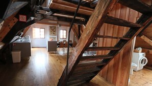 A rustic kitchen with wooden beams, a dining area, and a washing machine. - Apartment Soukenická 44 (Cesky Krumlov)