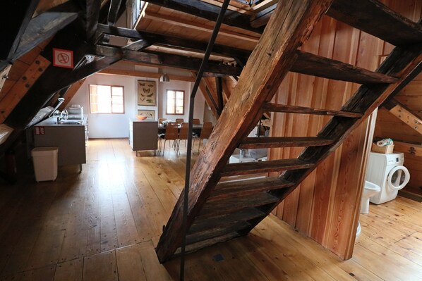 A rustic kitchen with wooden beams, a dining area, and a washing machine. - Apartment Soukenická 44 (Cesky Krumlov)