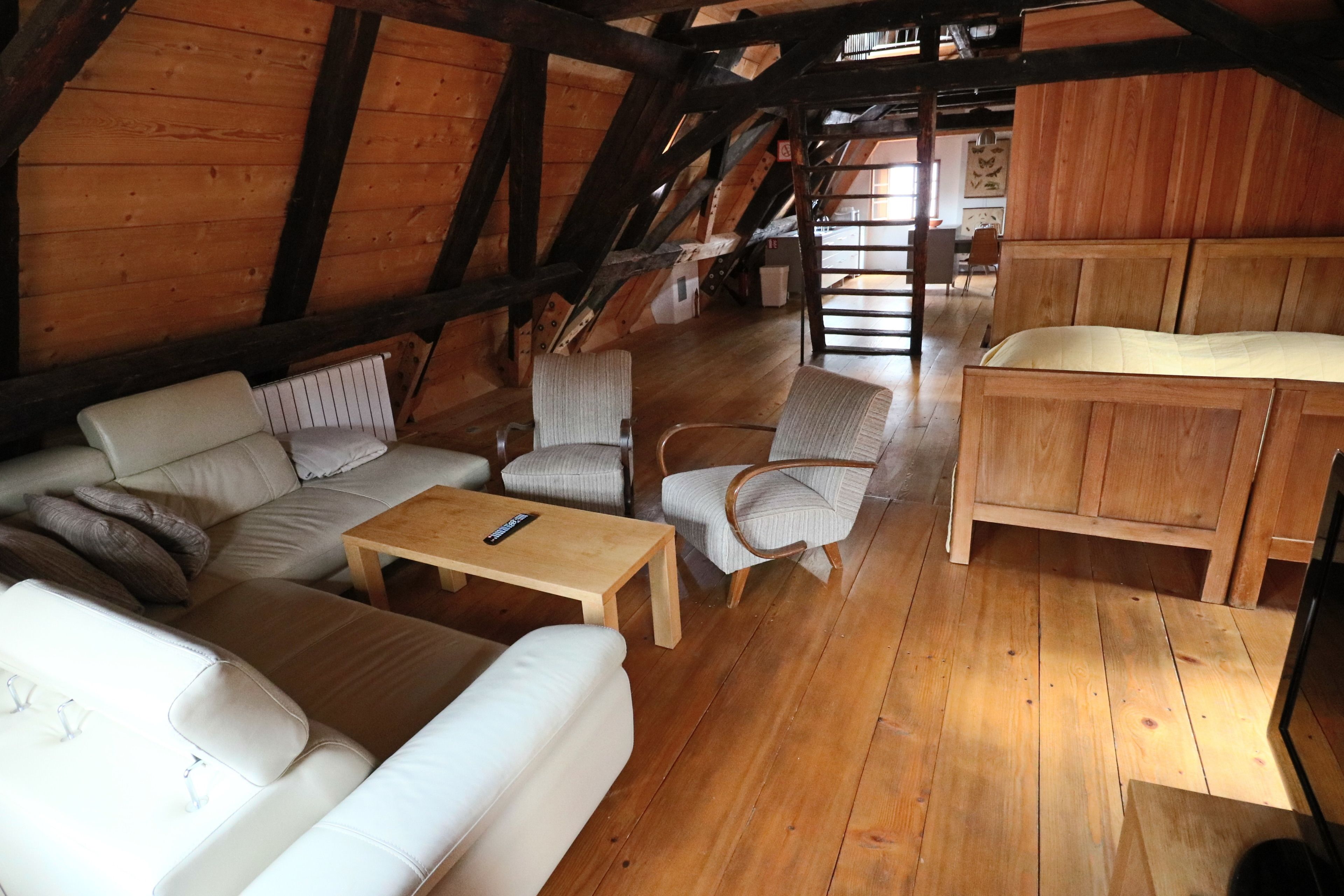 Ein Loft-Zimmer mit Holzbalken, einer Sofagarnitur, einem Holztisch und einem Holzschrank.