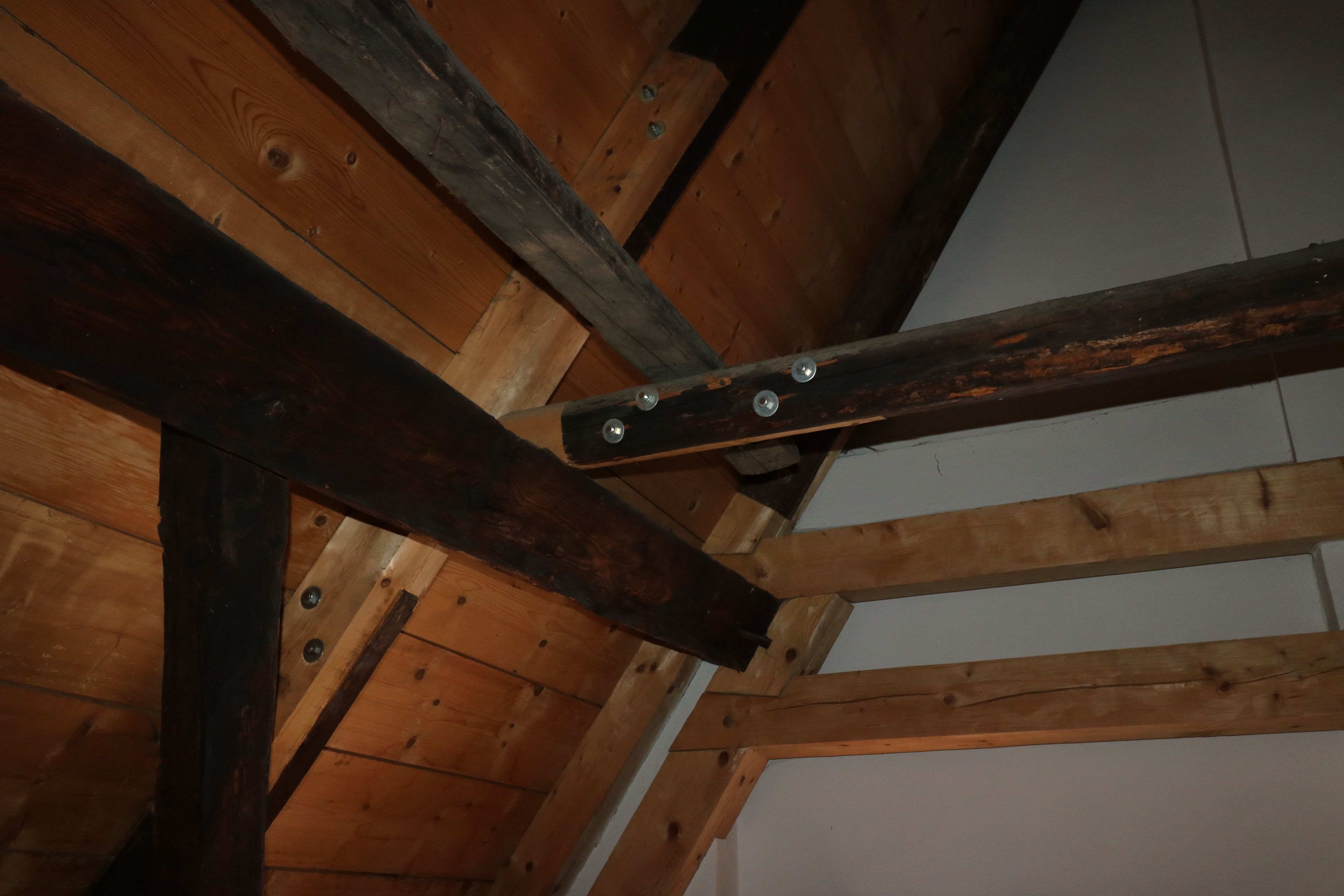 A wooden ceiling structure with visible beams and metal brackets.