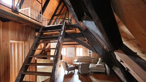 A wooden interior with a wooden staircase leading to an upper level. There is a sofa and a small table in the foreground. - Apartment Soukenická 44 (Cesky Krumlov)