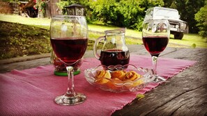 A picnic setup with wine glasses and a pitcher on a wooden table, surrounded by greenery. - Merkez Guest House (Brezice)