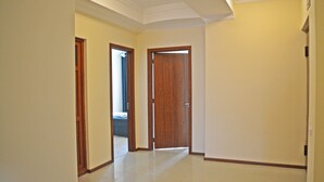 Un couloir avec une porte en bois, un interrupteur et un chambranle de porte.