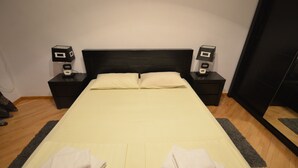 A neatly made bed with two pillows, two bedside tables with lamps, and a large mirror on the wall.
