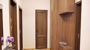A hallway with wooden doors, a radiator, and a small shelf with a plate and utensils.