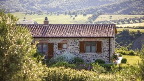 A stone house with a tiled roof, surrounded by lush greenery and a hilly landscape. - Farmhouse in the Tuscan countryside (Semproniano)