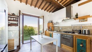 A kitchen with a sliding glass door to a balcony, wooden cabinets, a white countertop, and a built-in oven. - Farmhouse in the Tuscan countryside (Semproniano)