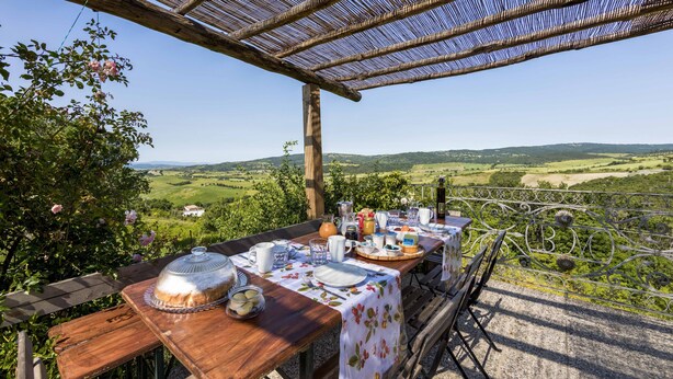 An outdoor dining area with a table set for breakfast, overlooking a scenic landscape. - Farmhouse in the Tuscan countryside (Semproniano)