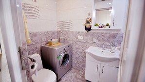 Une salle de bain équipée de toilettes, d’un lave-linge et d’un lavabo.