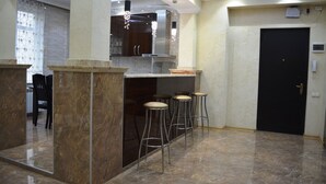 A modern kitchen with marble countertops, a central island, and bar stools. - Apartment on Ingorokva St. 19 (Tbilisi)