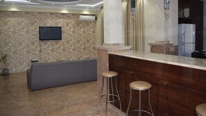 A modern kitchen with a marble countertop, two bar stools, a built-in oven, and a flat-screen TV mounted on the wall. - Apartment on Ingorokva St. 19 (Tbilisi)