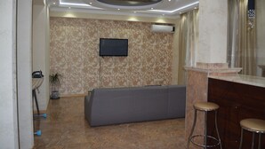 A modern hotel lobby with a sofa, bar stools, a flat-screen TV, and a patterned wall. - Apartment on Ingorokva St. 19 (Tbilisi)