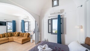Moderni hotellihuone, jossa on sänky, sohva ja näkymä kaupunkiin.