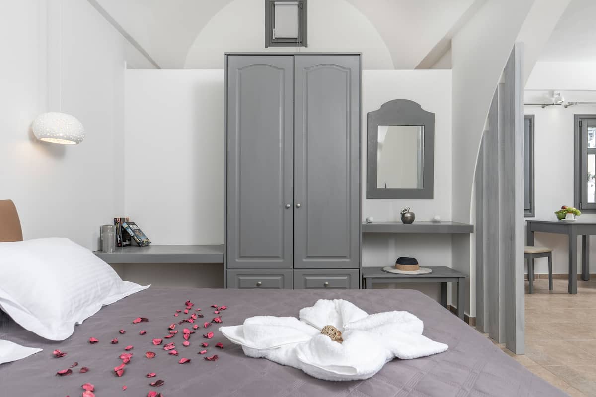 Ein Schlafzimmer mit Bett, grauem Kleiderschrank, Nachttisch und Spiegel.