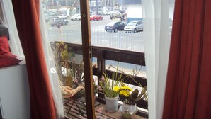 A view from a window with a white curtain, a balcony railing, and a street view with cars and buildings. - Habitaciones Florencia La Serena (La Serena)