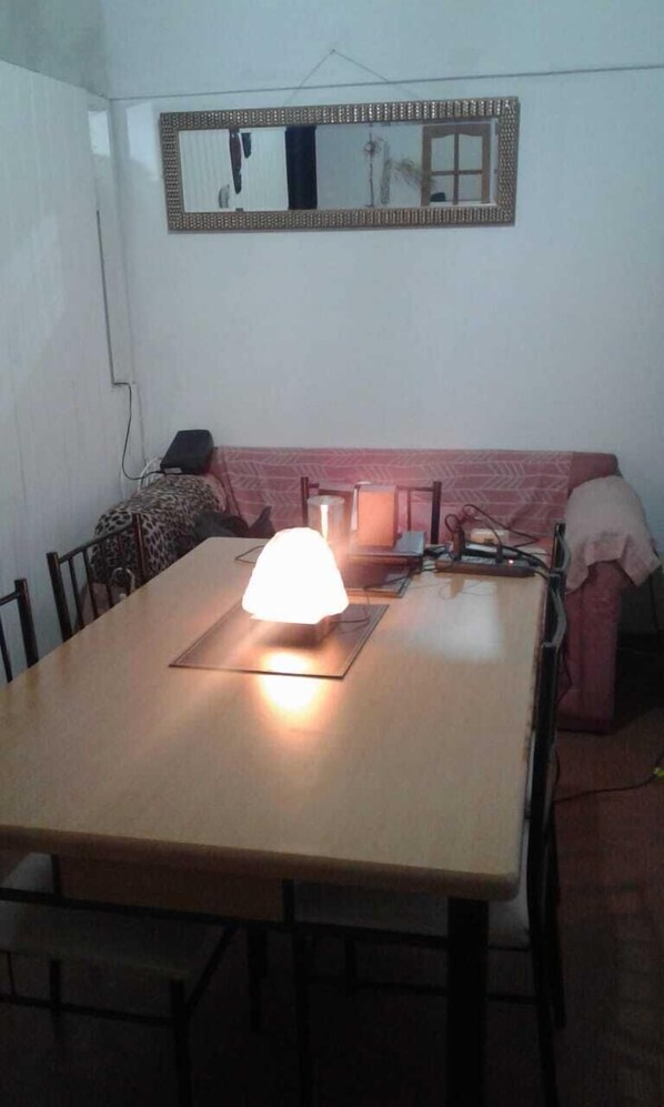 Un comedor con una mesa, sillas, un sofá y un espejo montado en la pared.
