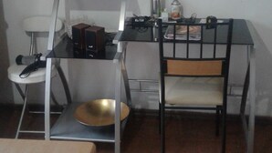 A kitchen area with a gas stove, a sink, a small table with a flower vase, and a welcome sign on the wall. - Habitaciones Florencia La Serena (La Serena)