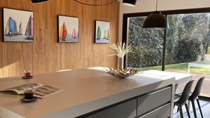 A modern kitchen with a large island, wooden ceiling, and artwork on the walls.