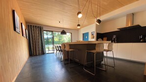 A modern kitchen with a central island, bar stools, and pendant lighting.