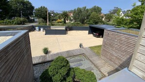 A backyard with a carport, a wooden deck, and a small garden area.