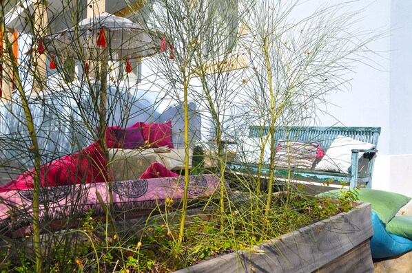 Un jardín con banco, cojines y vistas a un edificio.