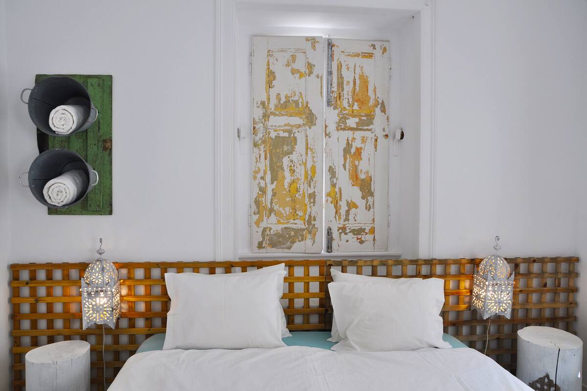 A bed with white linens, a wooden headboard, and two bedside lamps.
