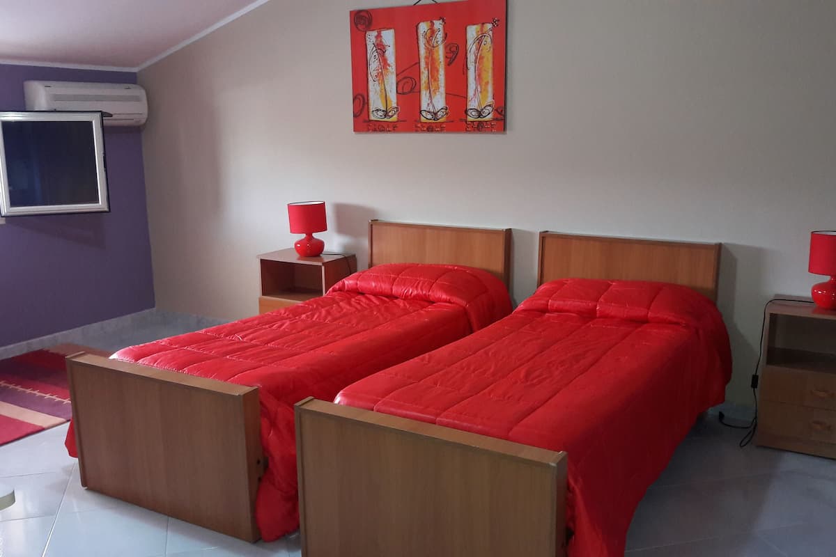 Una habitación con dos camas, un televisor y una obra de arte roja en la pared.